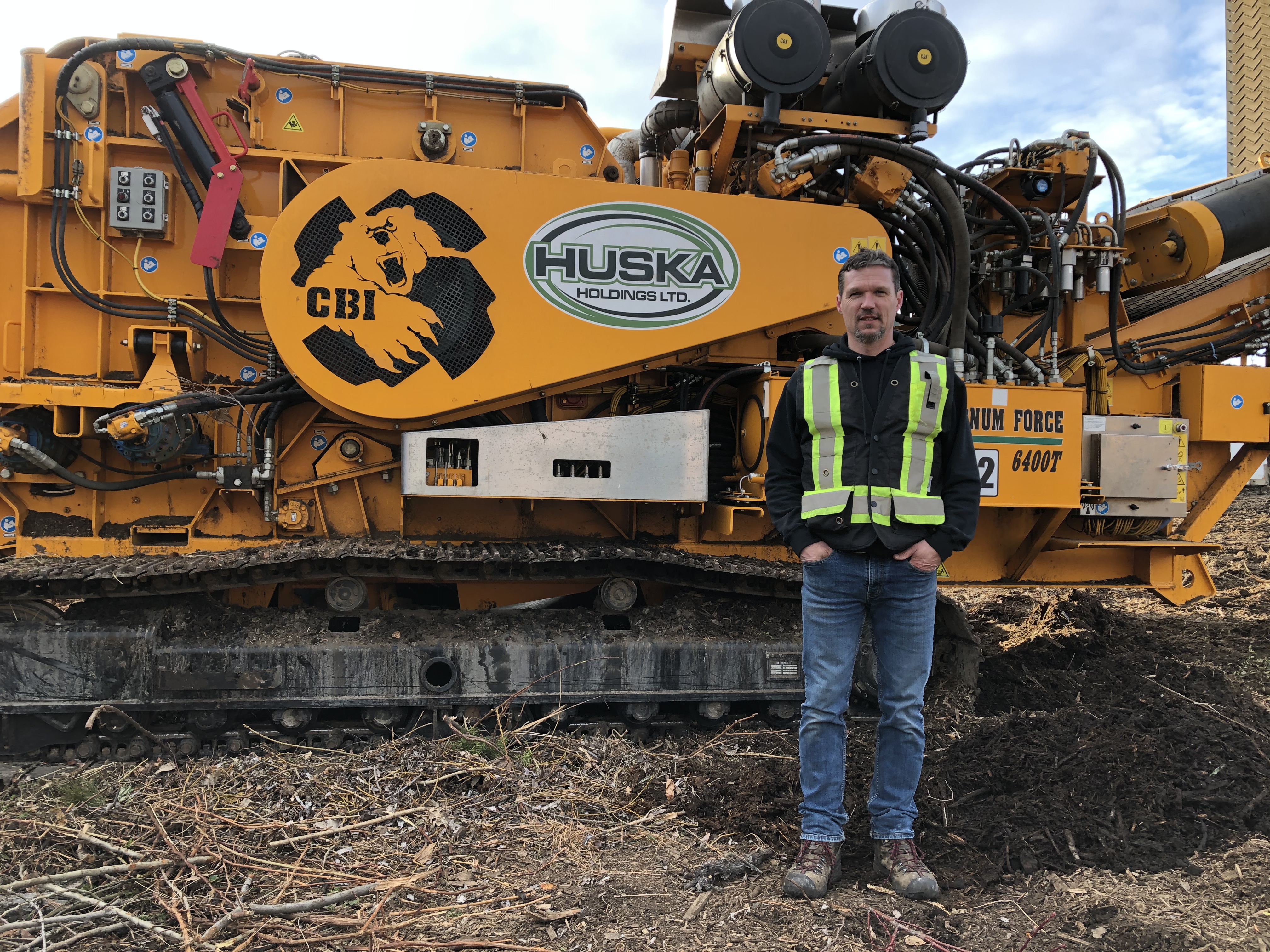 Justin Huska standing in front of one of their CBI Horizontal Grinders