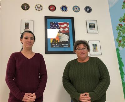 Nicole and Barbi standing in front of CBI's Veterans wall.